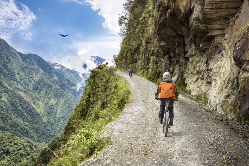 Persona en bicicleta por una carretera de montaña sin asfaltar.